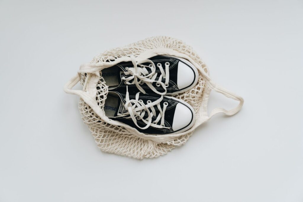 Stylish black sneakers placed in a mesh bag on a clean white background, showcasing minimalist design.