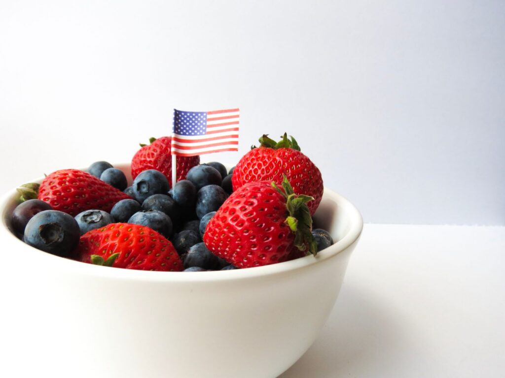 A delicious bowl of strawberries and blueberries adorned with a small American flag, perfect for patriotic celebrations.