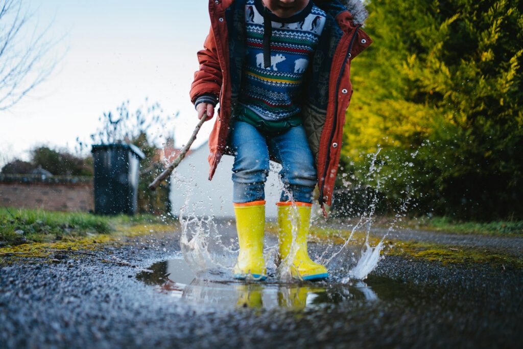 Kid in red jacket and blue denim jeans running on water