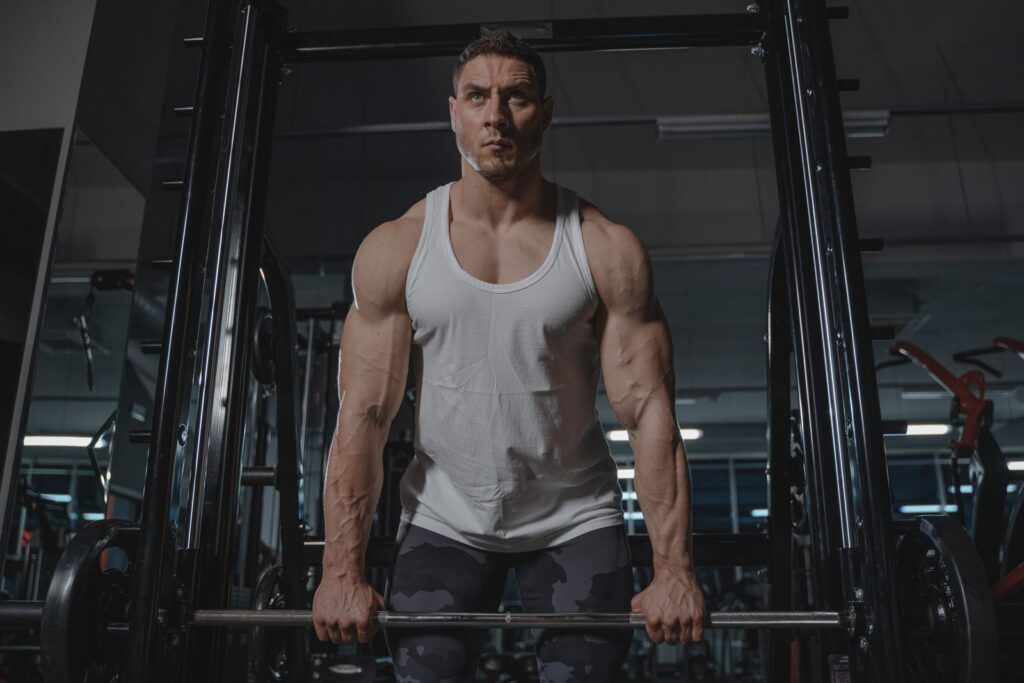 Male bodybuilder lifting weights during workout in gym. Intense focus and physical strength displayed.