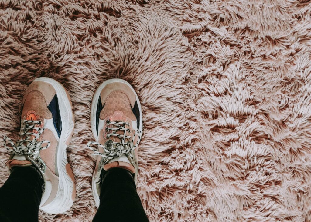 A pair of trendy sneakers on a fluffy shag carpet, blending comfort and style.