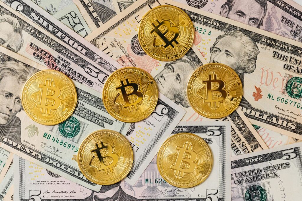 Gold bitcoins placed on a background of US dollar bills representing cryptocurrency and traditional finance.