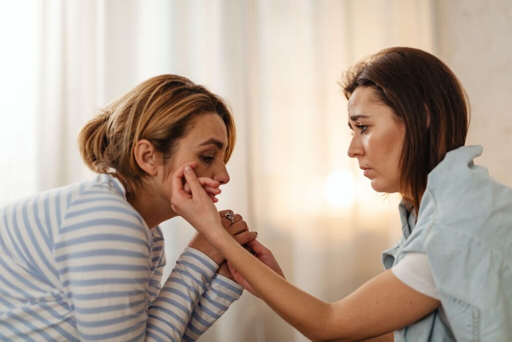 Two women comfort each other, depicting empathy and support in an intimate setting.