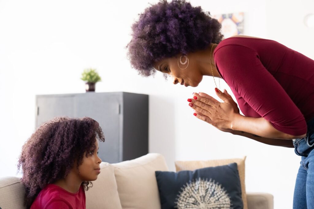 A touching moment between a mother and her daughter indoors, emphasizing family bonds.