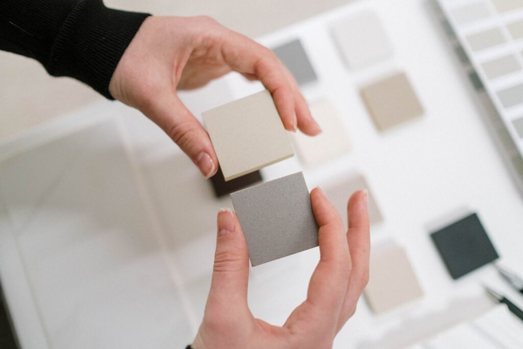 Hands holding neutral color swatches for interior design selection.