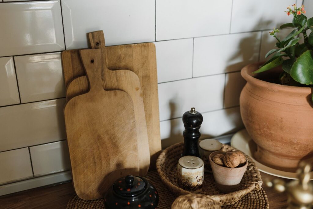 A warm kitchen corner featuring wooden chopping boards, a pepper mill, and a potted plant for rustic charm.