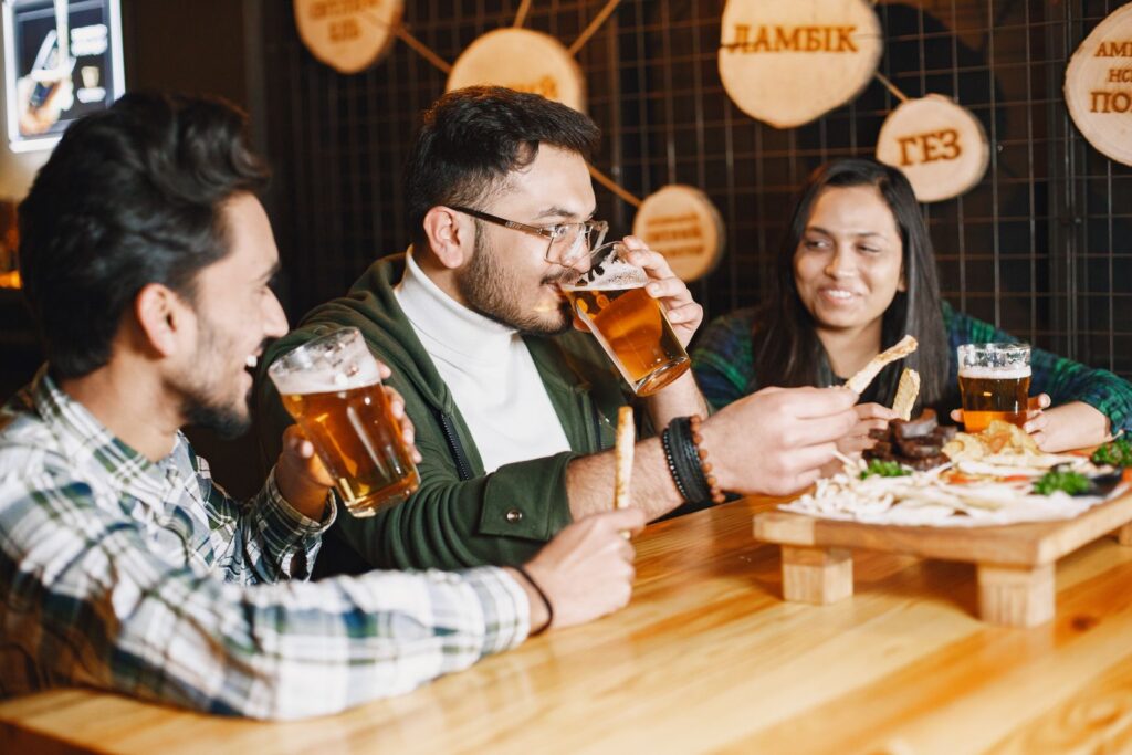 Friends at a pub sharing drinks and snacks, smiling and socializing.