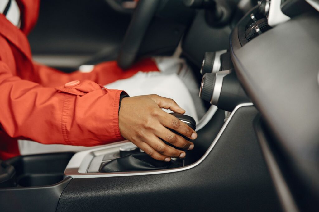 Close-up view of a person shifting gears in a car interior, illustrating driving expertise.