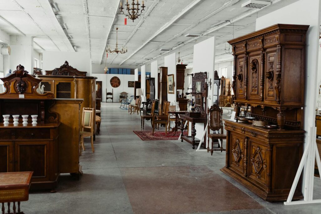 A spacious showroom filled with various antique wooden furniture pieces on display.