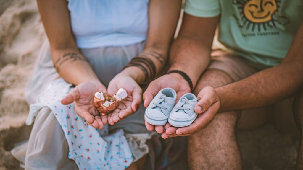 A touching moment captured of expecting parents showcasing baby shoes, symbolizing a new chapter.