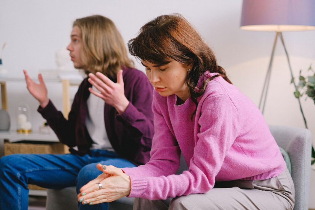 Parent sitting quietly while teen vents nearby in a living room