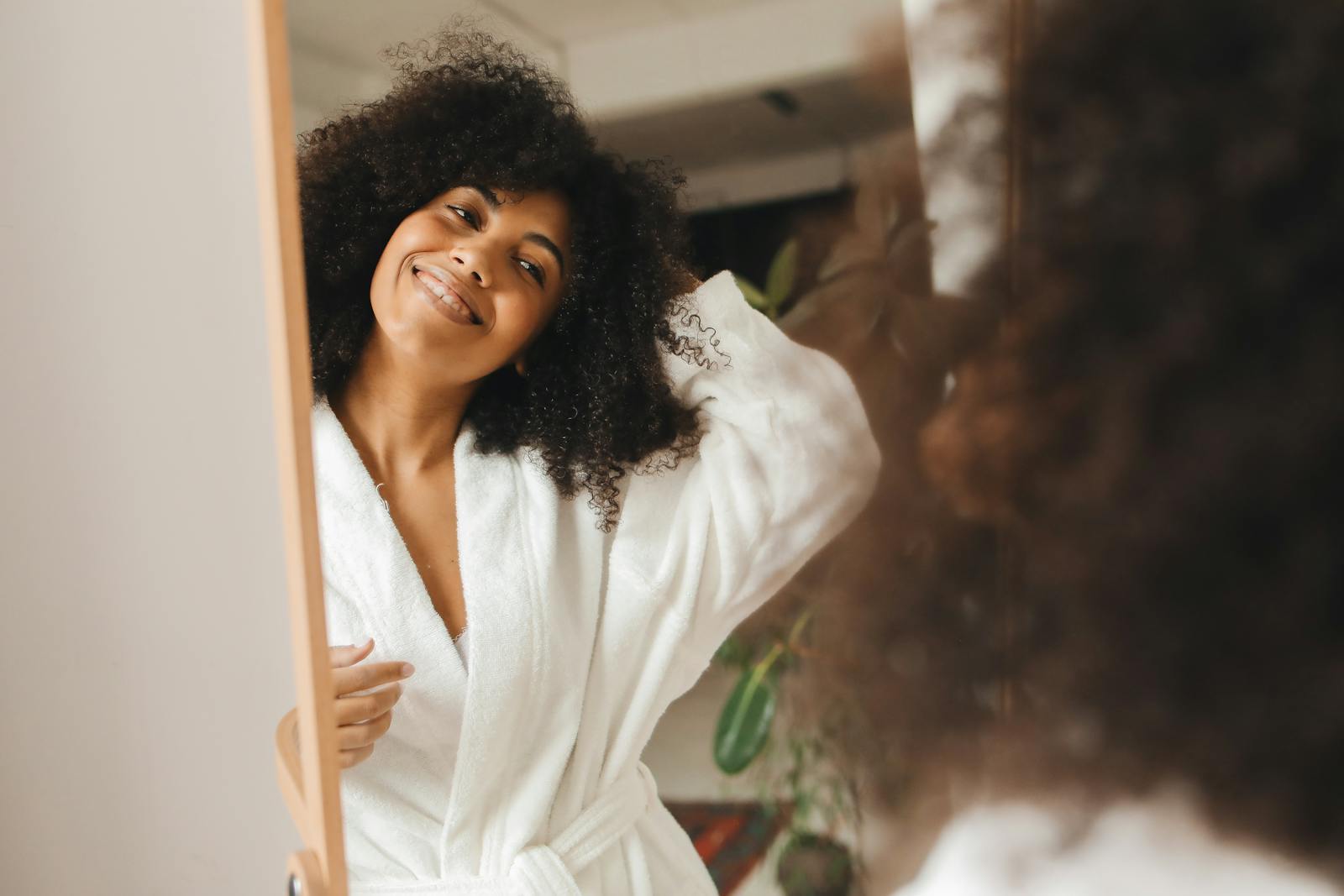 Happy woman with curly hair smiling in a bathrobe at home.