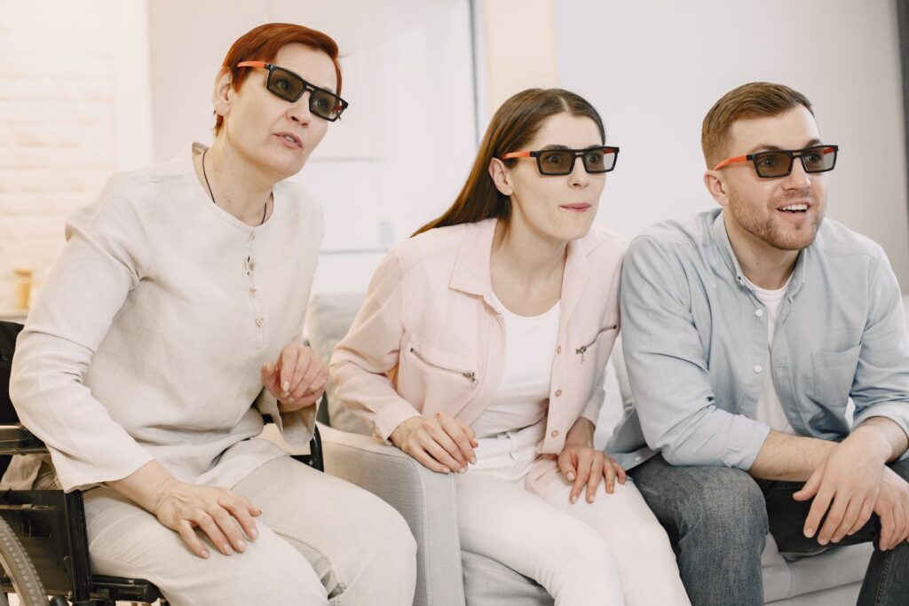 Three people enjoying a 3D movie experience at home while seated on a sofa.
