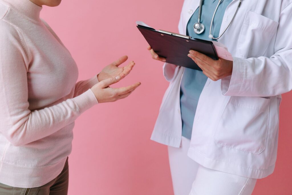 Close-up of a patient consulting a doctor with a clipboard in a medical setting.