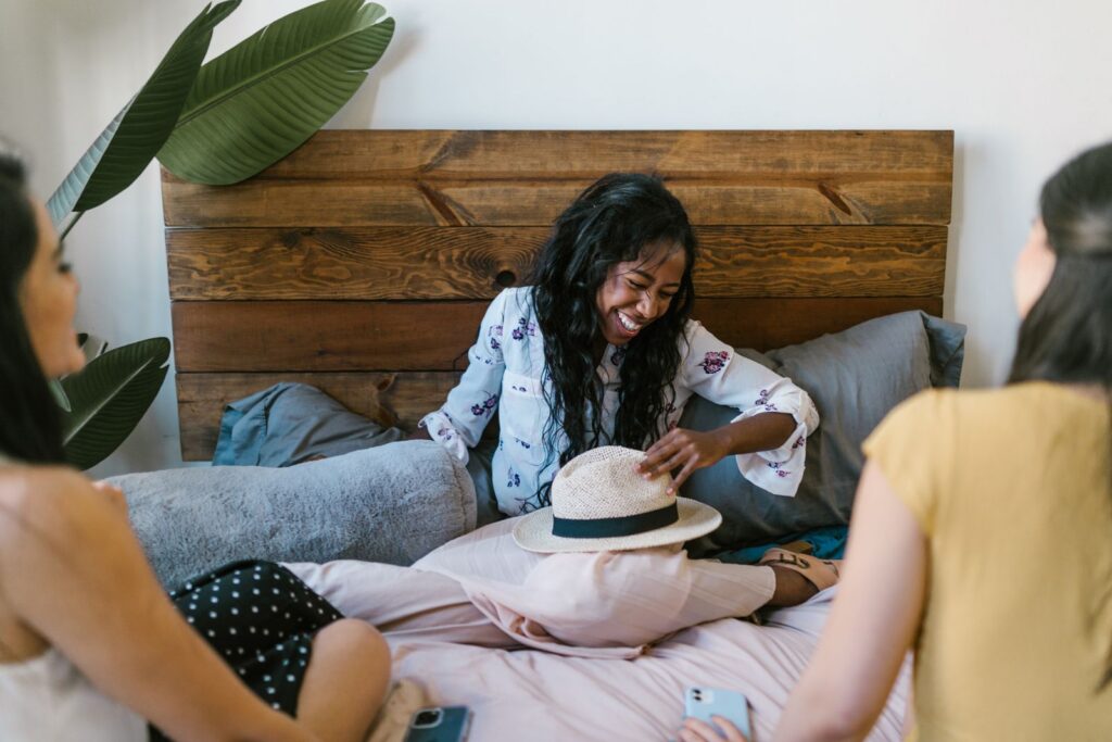 Three friends laughing and bonding indoors, sharing a joyful moment together.