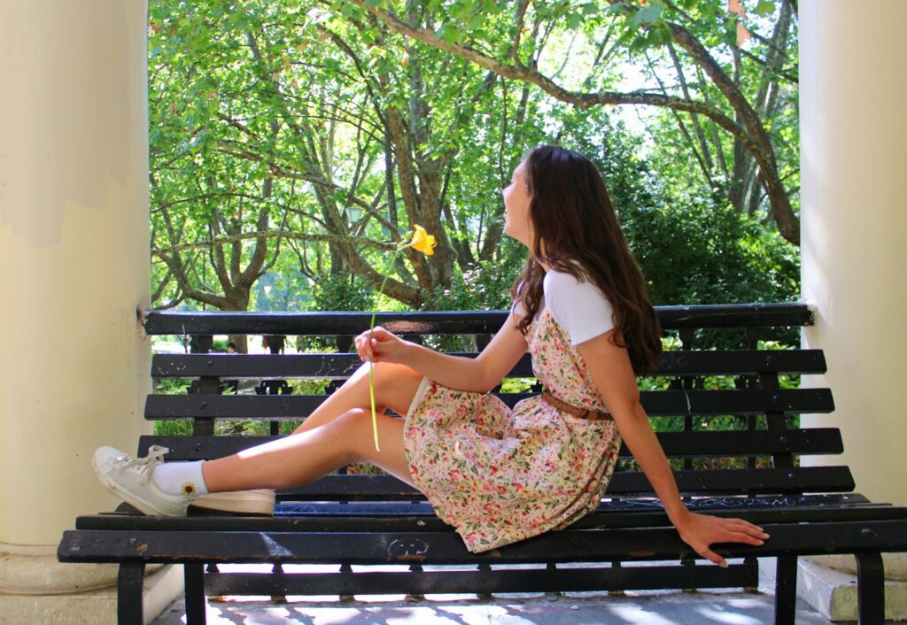 a girl sitting on a bench in a park