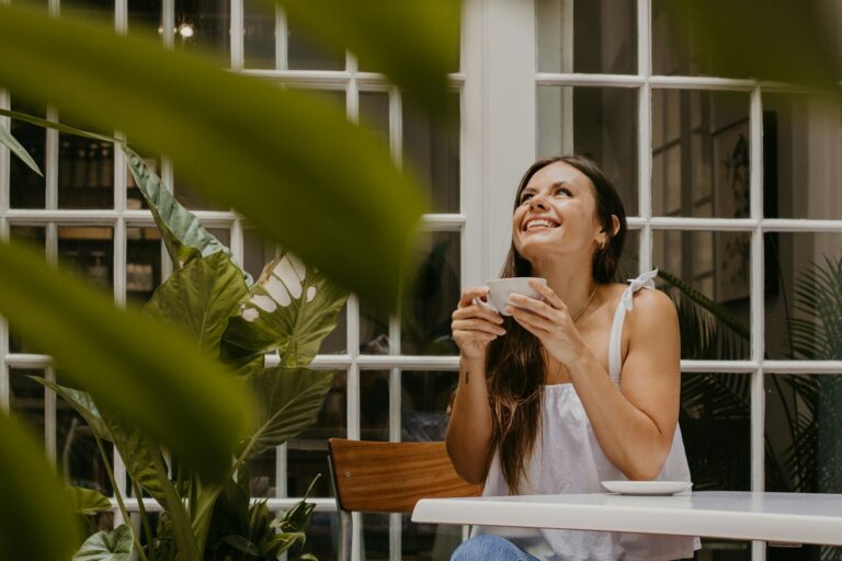 a woman sitting at a table drinking a cup of coffee