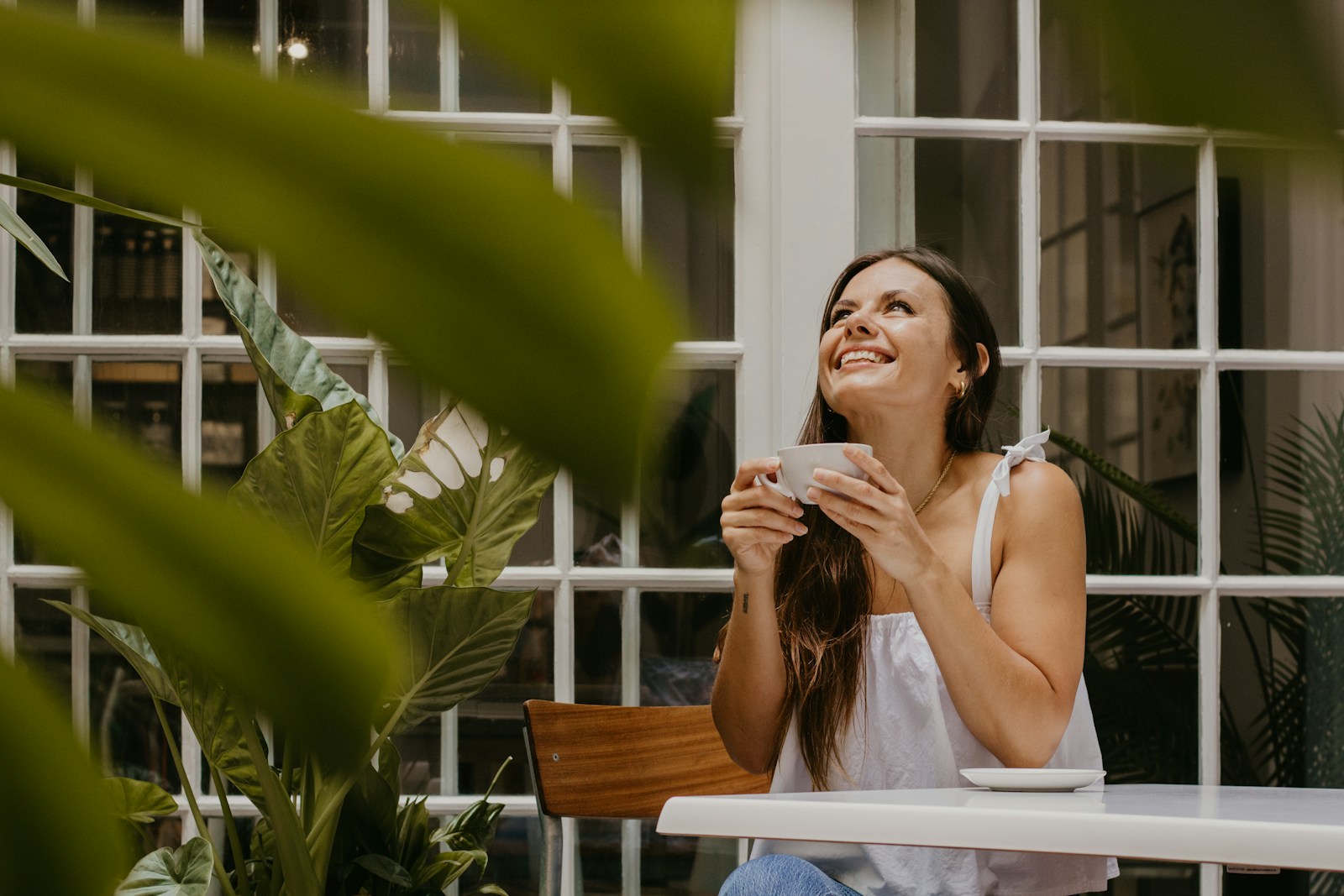 a woman sitting at a table drinking a cup of coffee