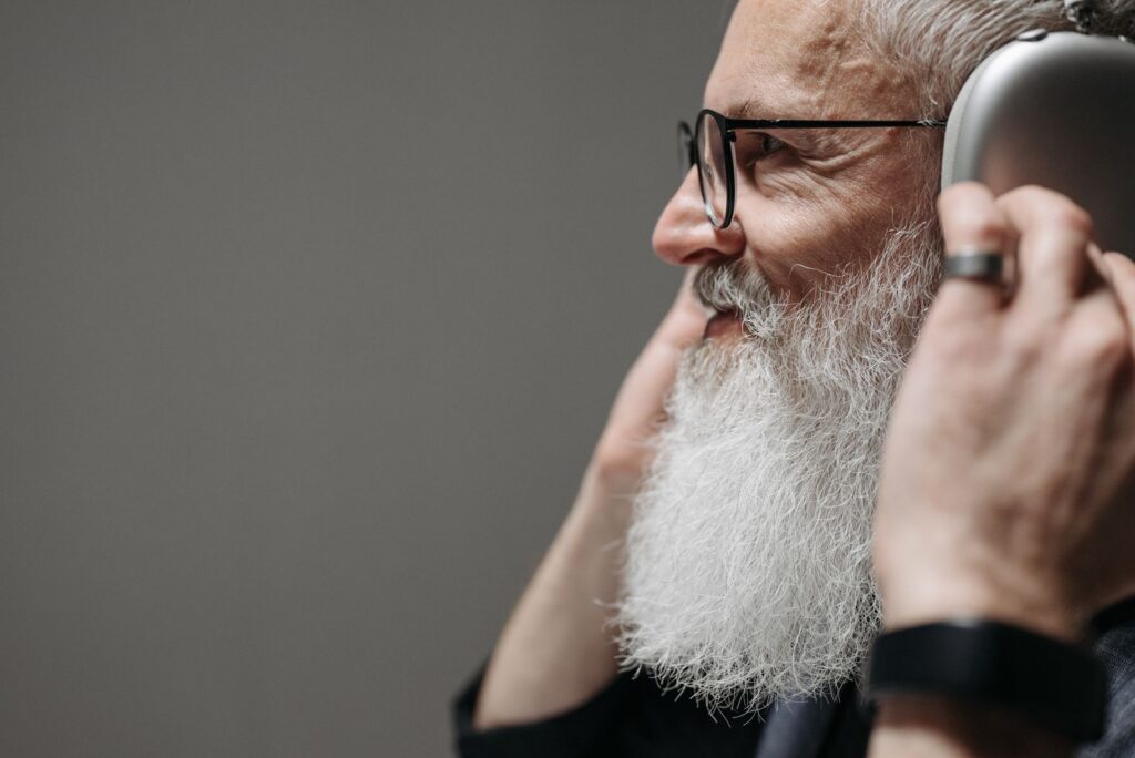 Profile of an adult man with a beard and glasses, listening to music with large headphones.