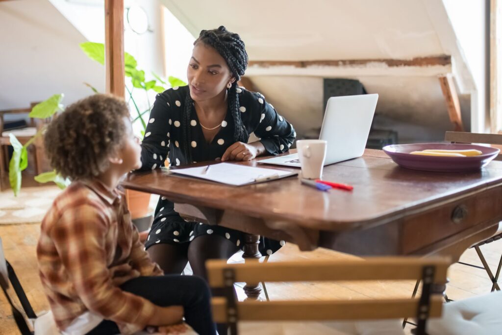 A mother and son spending quality time together at a table, engaged in conversation and homework.