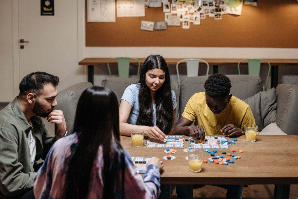 A group of friends enjoying a board game with drinks at a cozy table setting.