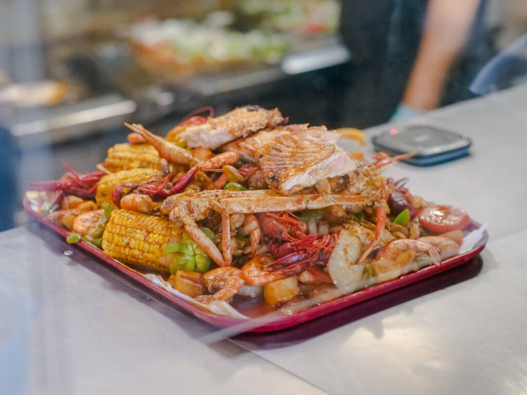 A delicious seafood boil platter with crab, shrimp, corn, and vegetables in a vibrant setting.