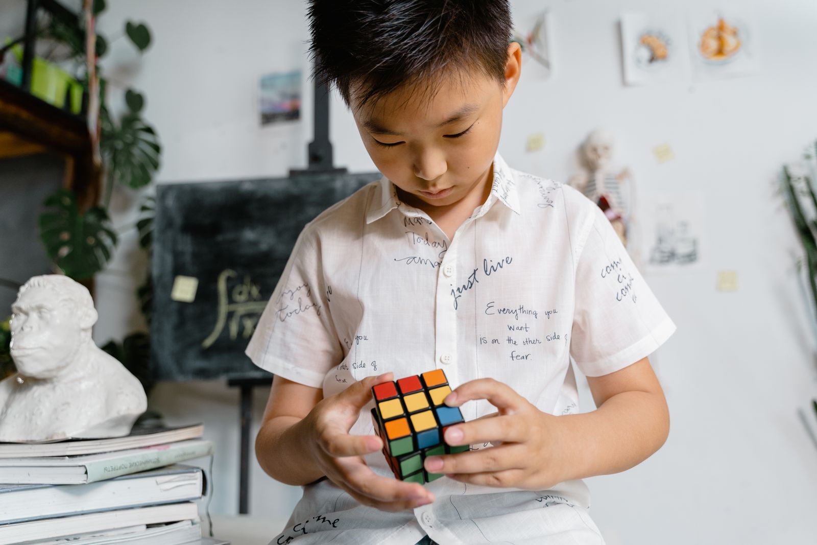 A young boy intensely solving a Rubik's Cube in a well-lit indoor setting, focused on the task.