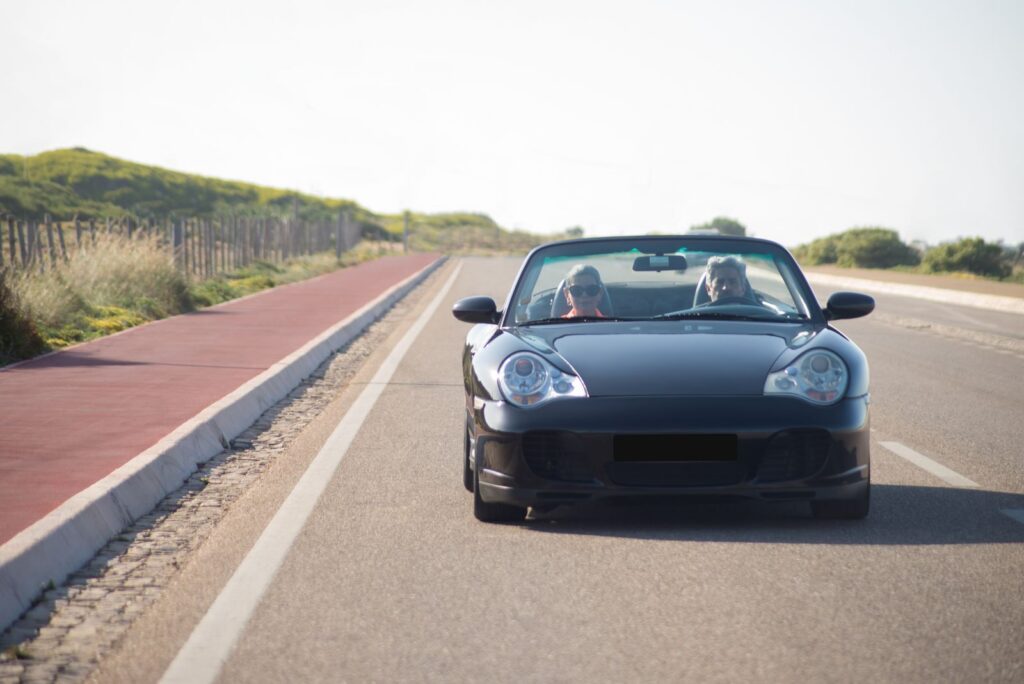 Senior couple enjoy a scenic drive in a convertible, capturing the essence of adventure in Portugal.