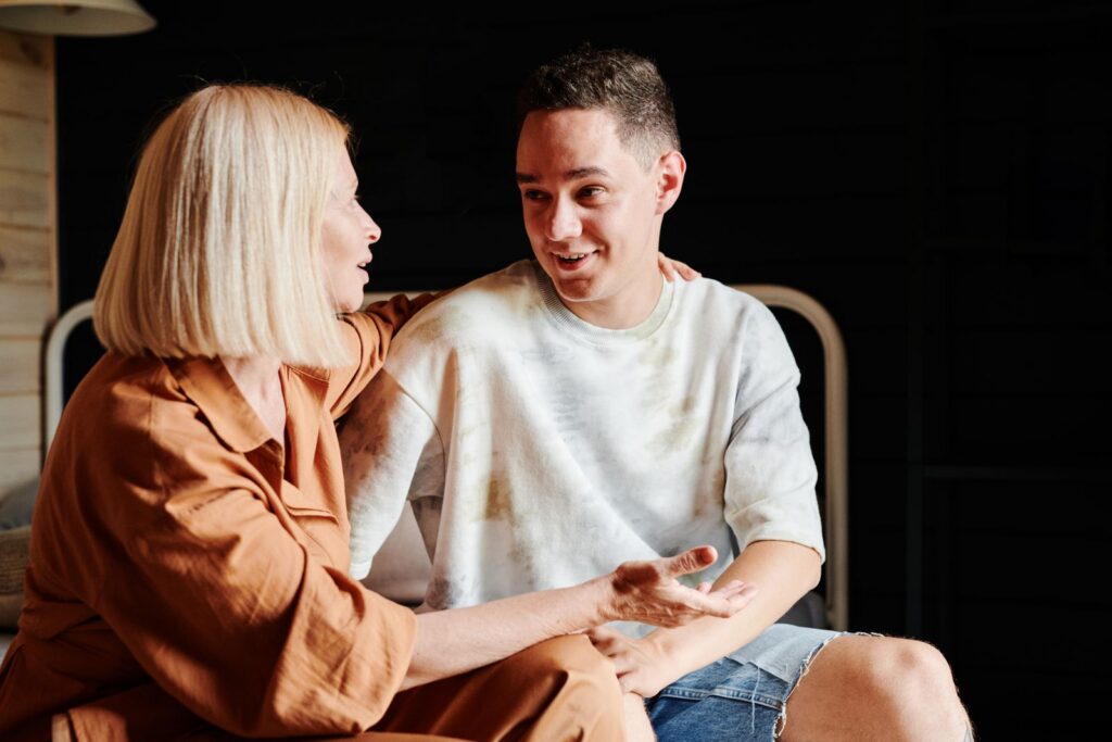 A mother and son engage in a warm, heartfelt conversation indoors.