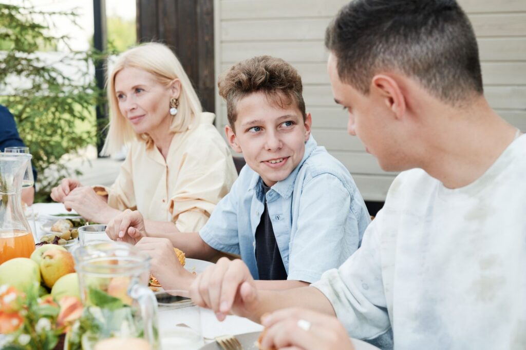 A family gathering outdoors sharing a meal, engaging in lively conversation.