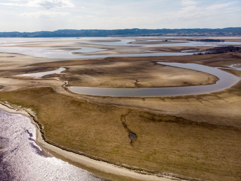 Aerial view of a vast, drying lake and riverbed, illustrating environmental change.