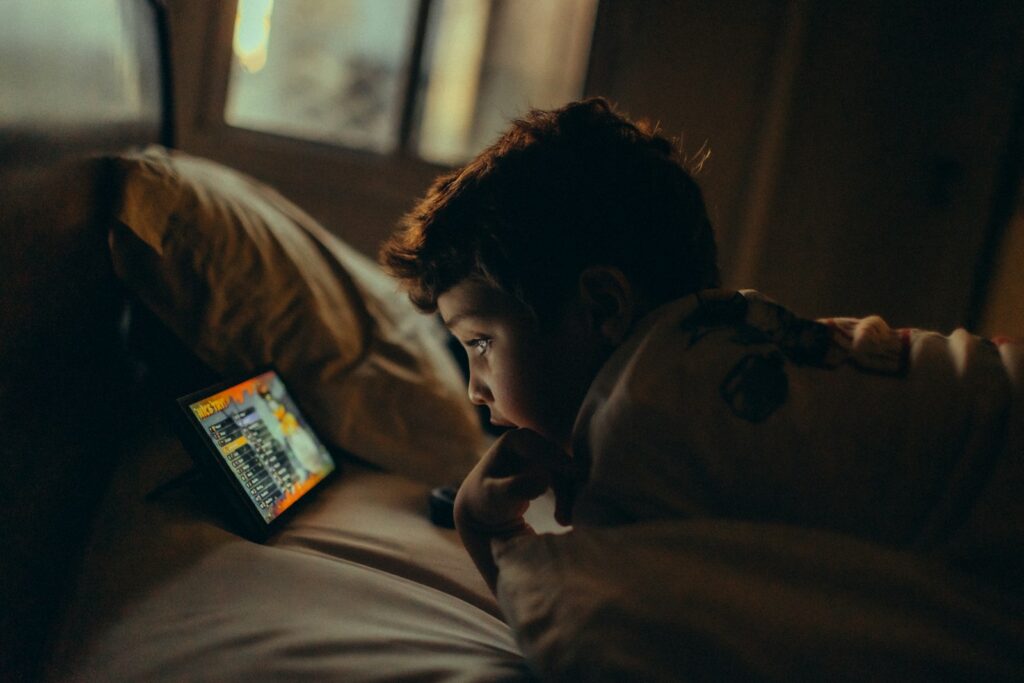 Young boy watches a tablet in bed at night
