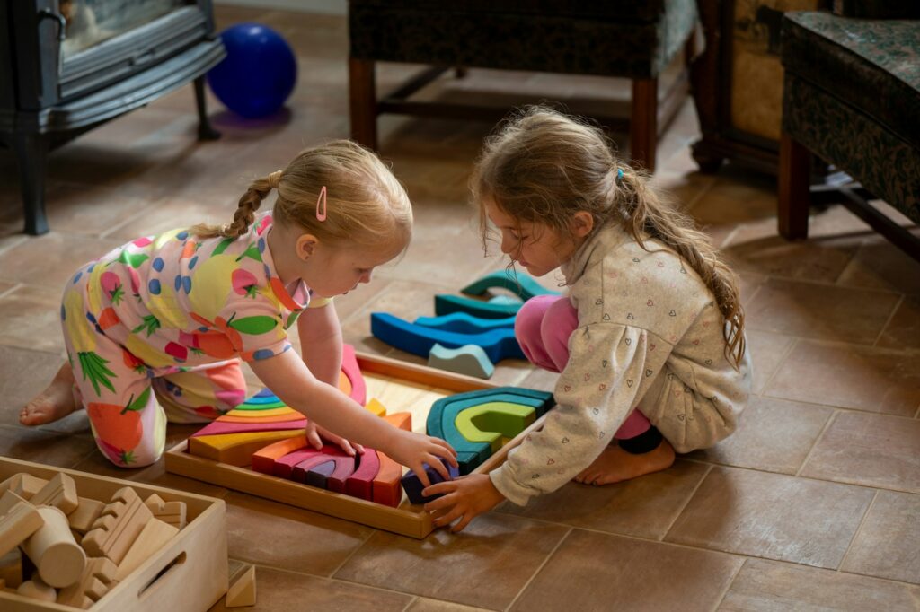 Two young girls playing with colorful wooden blocks.