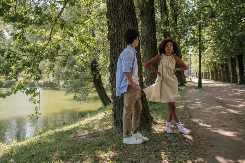 Teen couple in a park by a lake, enjoying a sunny day and each other's company.