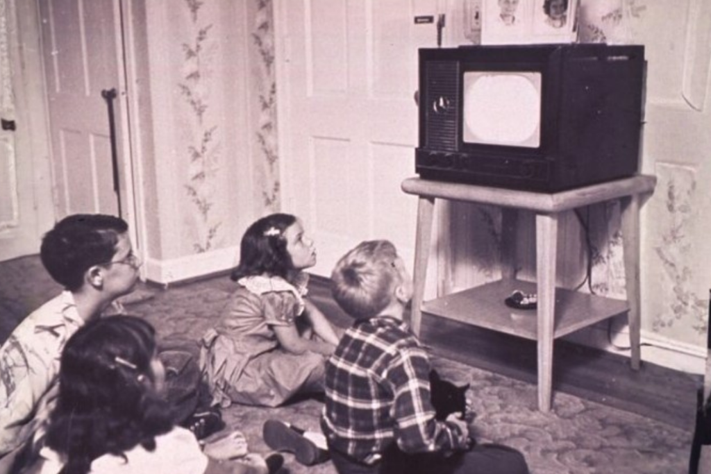 a group of children sitting on the floor in front of a tv