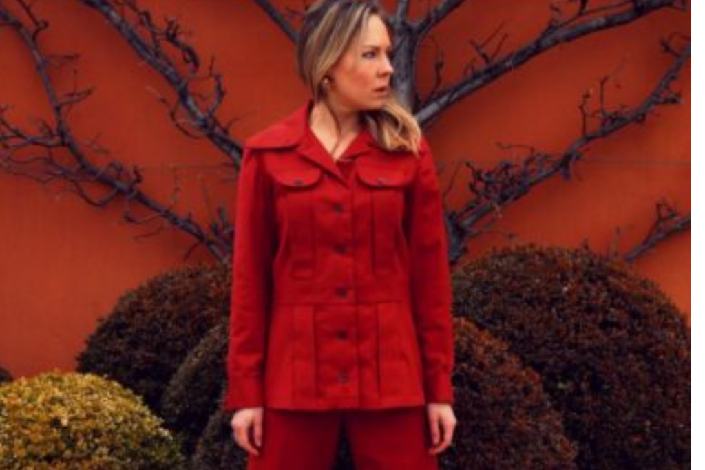 Stylish woman in a red suit posing against a vibrant wall in Chicago.