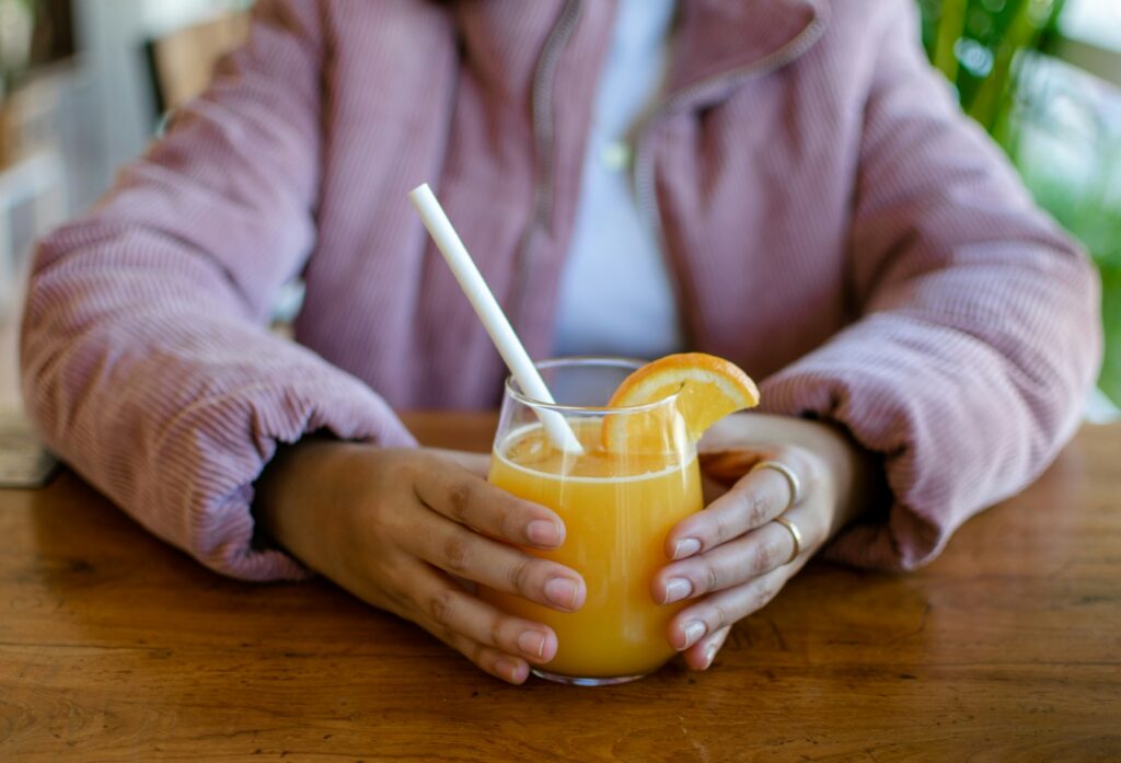 a woman holding a glass of orange juice