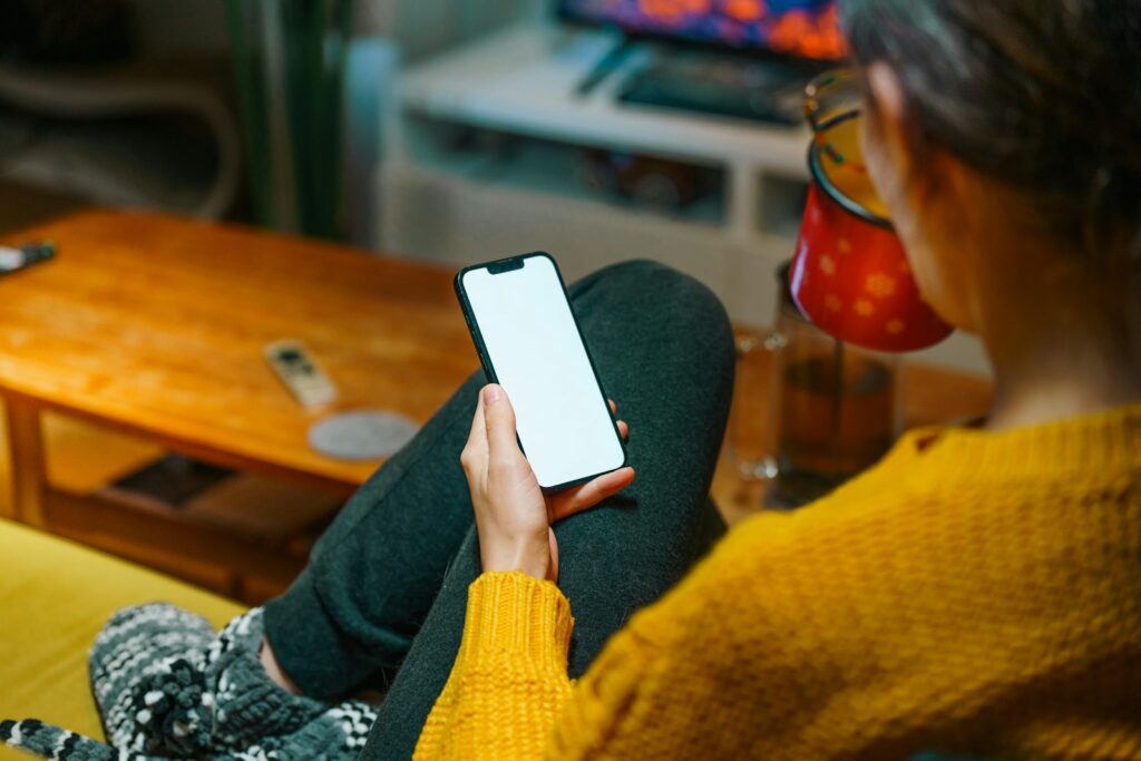 Woman uses phone while drinking tea.