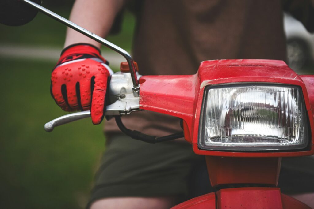 Person in red gloves riding a red scooter