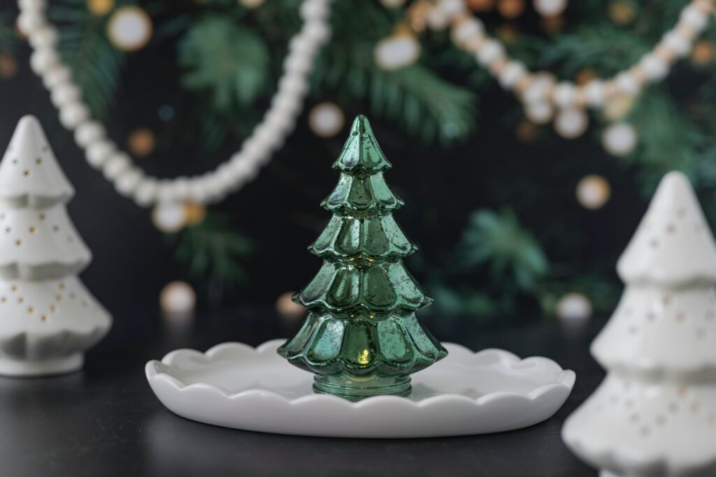 Green glass christmas tree on a white dish.