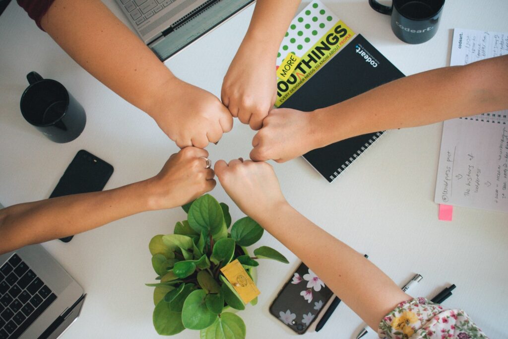 five fists bumping over office desk