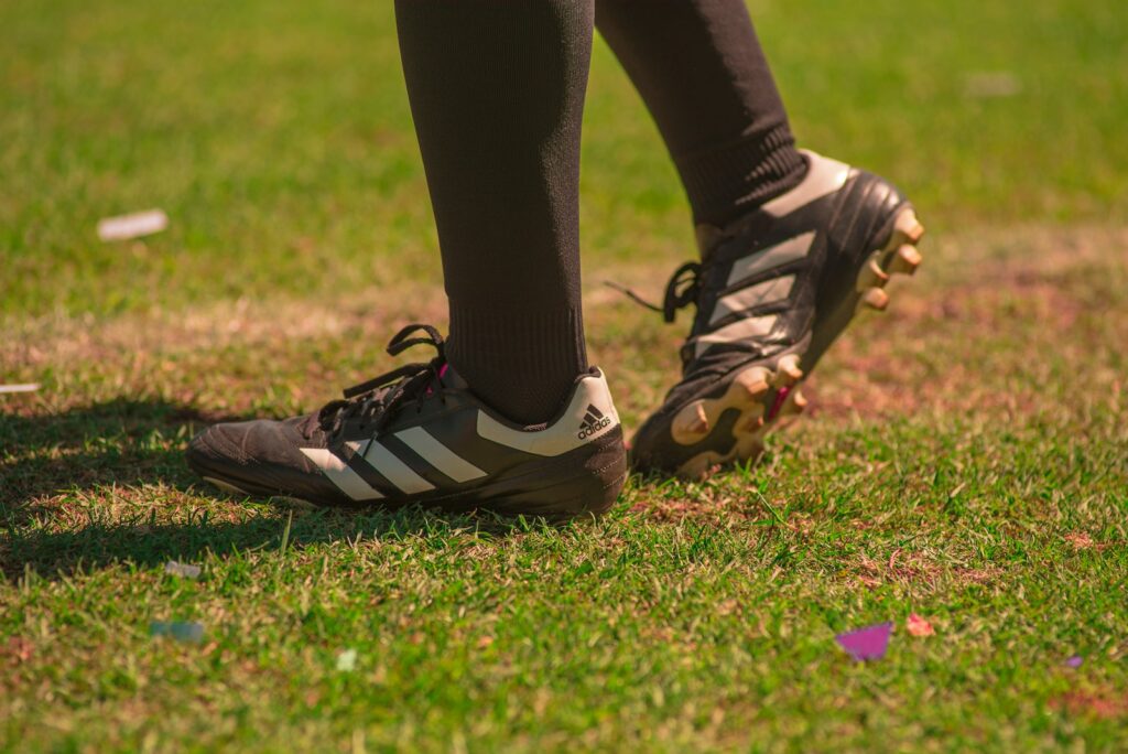 person wearing black-and-white adidas cleats standing on field