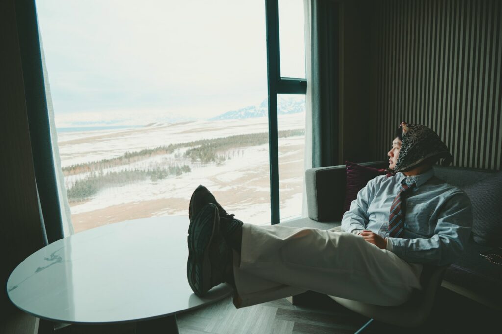 Man in suit looking out window at snowy landscape