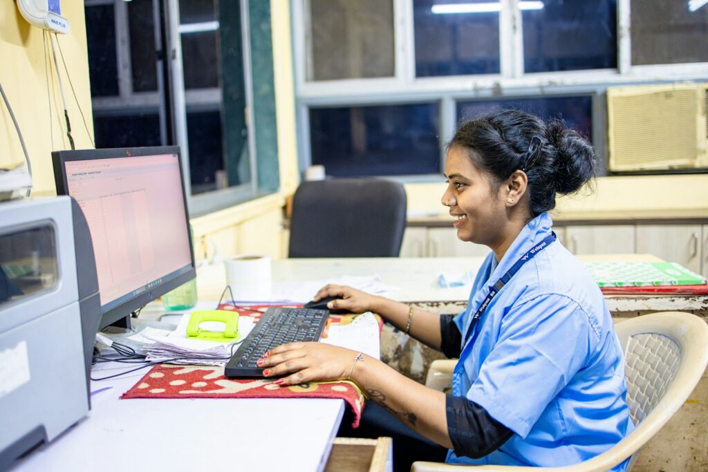 A woman smiles while working on a computer.