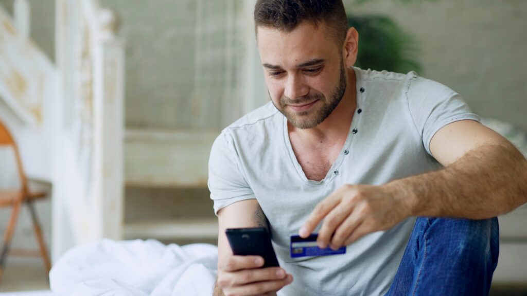 Man using phone and credit card for online shopping.