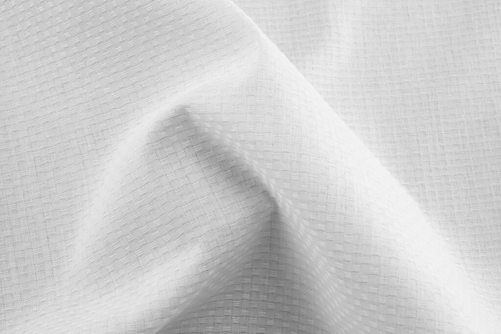 Close-up of tightly woven white cotton sheet fabric showing fine thread texture