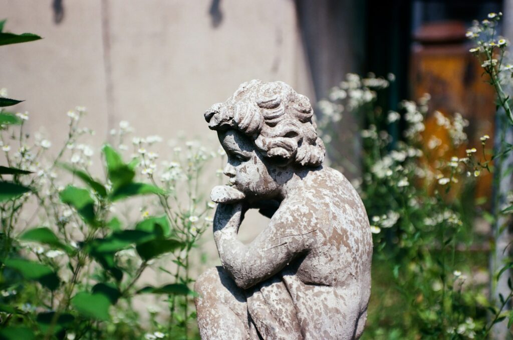 a statue of a man holding a bird in a garden