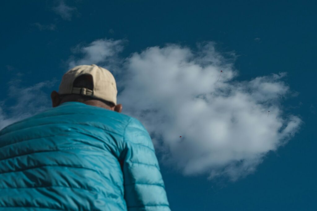 Person in a blue jacket looking at a cloud.
