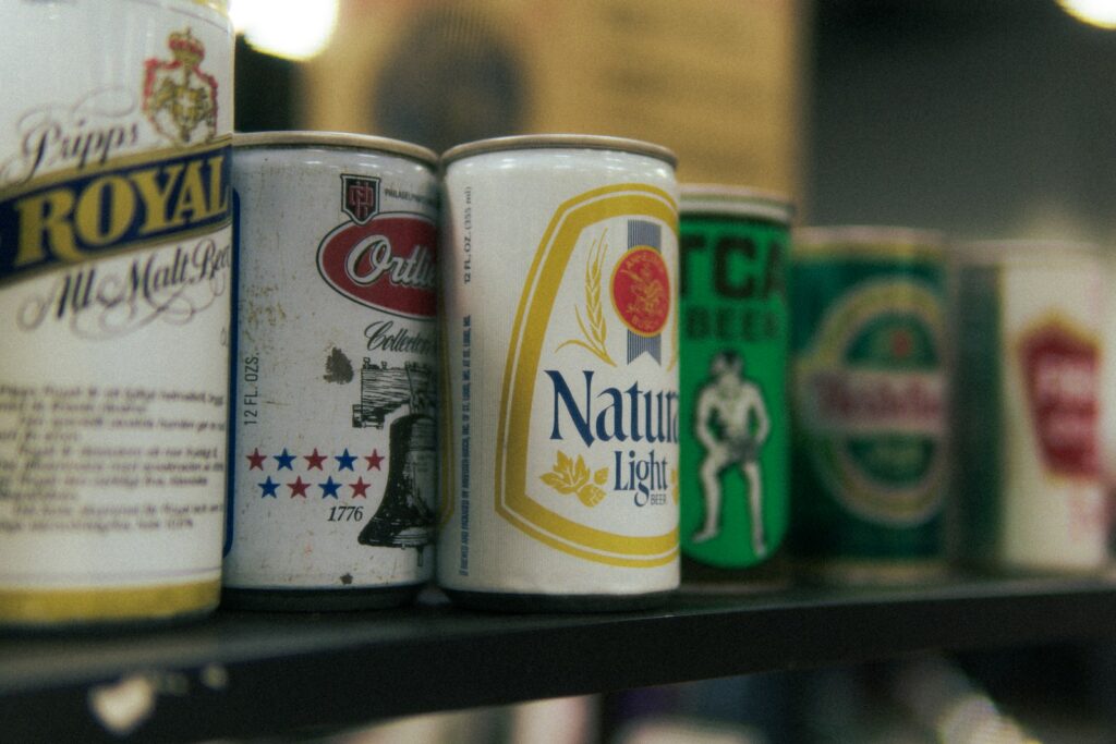 A row of vintage beer cans displayed on a shelf.