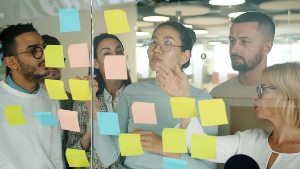 Diverse team collaborating on sticky notes.